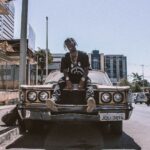 photo of man sitting on car hood