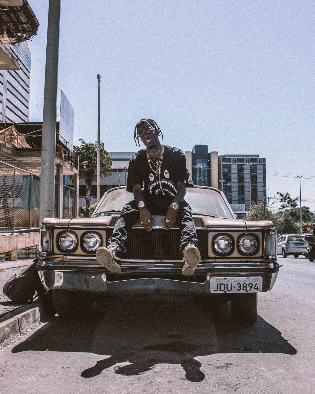 photo of man sitting on car hood