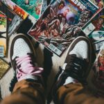 crop person standing on pile of collection of comics books